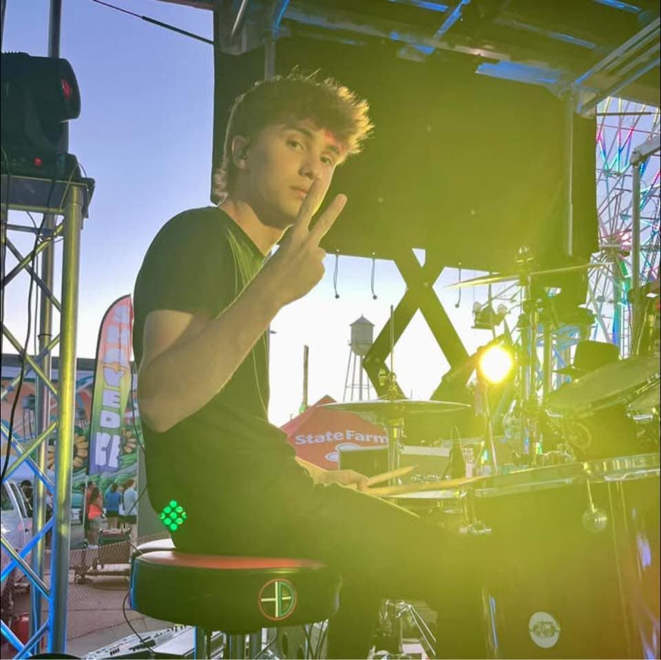 Brody Bates behind a drum kit on an outdoor stage