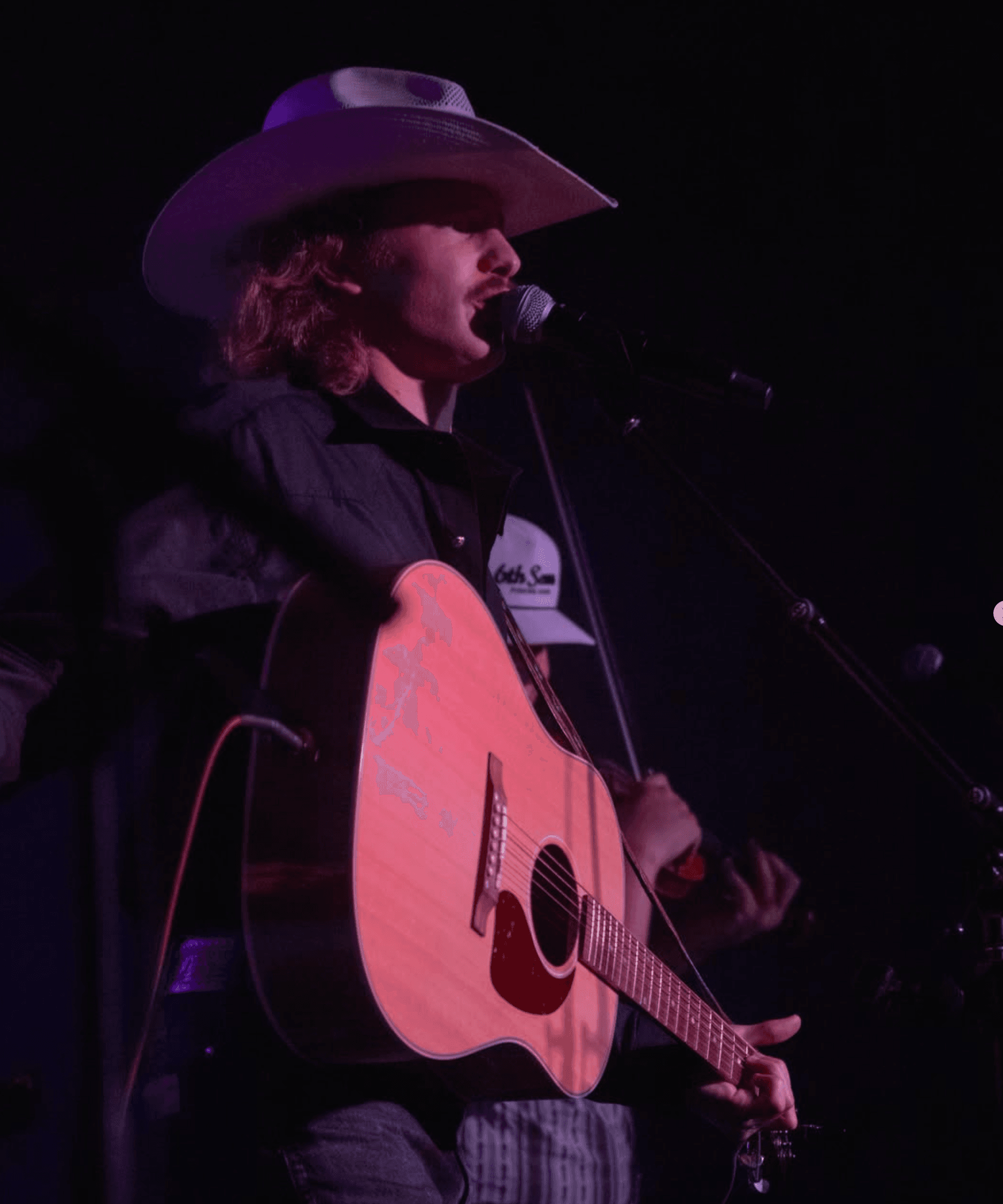 George Arbuckle singing and playing acoustic guitar onstage