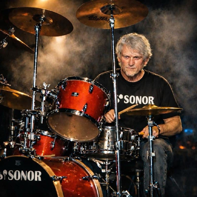 Alex Austyn playing drums onstage behind a red Sonor drum kit