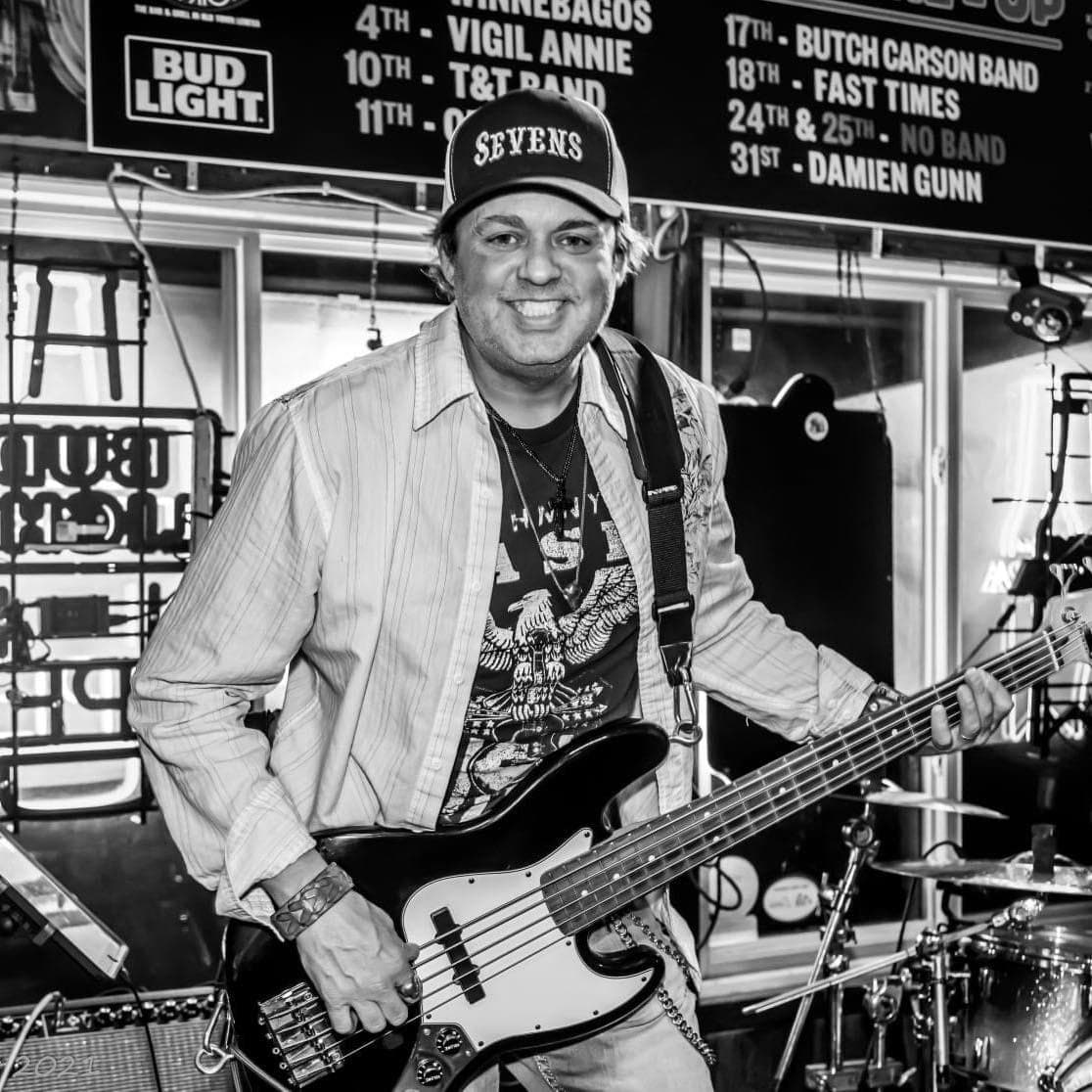 Scott Evans smiling while playing bass guitar onstage